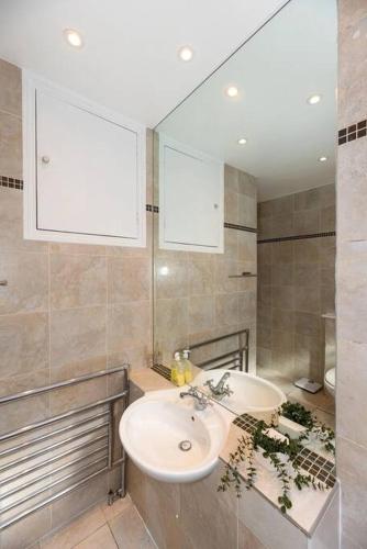 a bathroom with a sink and a mirror at Discover London Central 2 Bedroom in Kensington in London