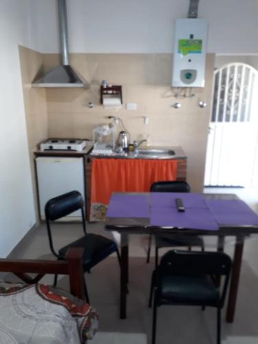 y cocina con mesa, sillas y fogones. en Departamento JANA 2, en Alta Gracia