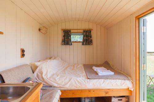 a small room with a bed and a sink at Daisy Shepherds Hut in Kent