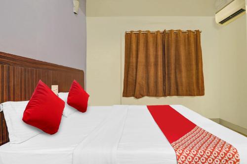 a bedroom with a white bed with red pillows at Hotel O HRR Hotels Near Paradise circle in Hyderabad