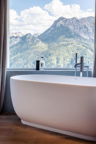 a bath tub in front of a window with a mountain view at Boutiquehotel Blaue Burg Falkenstein in Pfronten