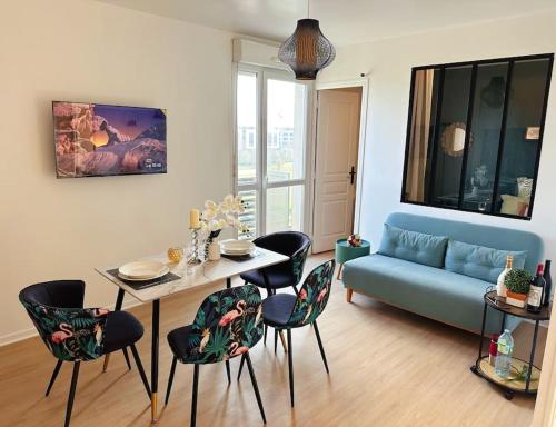 un salon avec un canapé bleu, une table et des chaises dans l'établissement Bon apart 5 min from Disneyland & village Paris, à Montévrain
