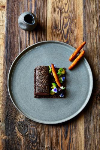 a plate with a piece of chocolate cake and carrots at Boutiquehotel Blaue Burg Falkenstein in Pfronten