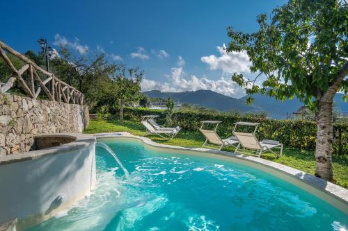 a swimming pool with two chairs and a stone wall at Villa Prota in Vico Equense