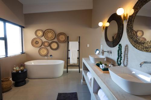 a bathroom with two sinks and a tub and mirrors at Marepe Mountain View in Kampersrus AH