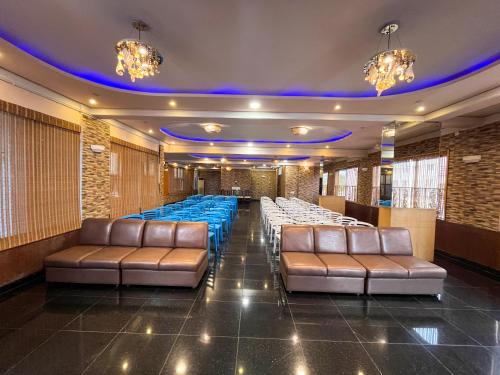 a banquet hall with leather chairs and blue tables at Ananya Comfortss in Hospet