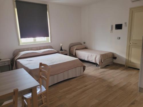 a room with two beds and a table and a window at HOUSE AIRPORT Catania in Catania