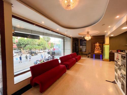a waiting room with red chairs and a large window at Ananya Comfortss in Hospet