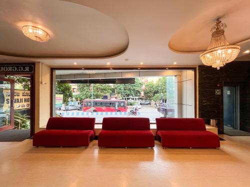 a lobby with two red chairs and a large window at Ananya Comfortss in Hospet