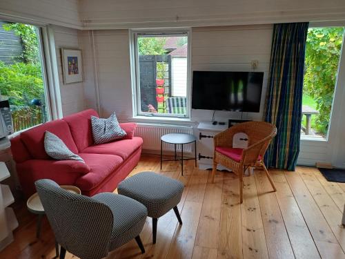 a living room with a red couch and a tv at Vrije Vogels tuin met privacy in Warmenhuizen