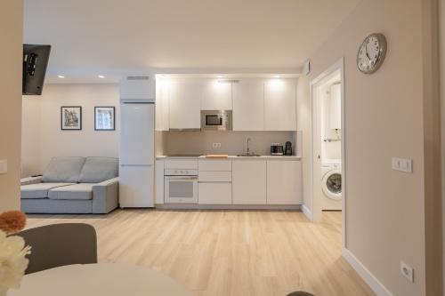 eine Küche und ein Wohnzimmer mit weißen Schränken und einem Sofa in der Unterkunft HALO Vigo CUATRO in Vigo