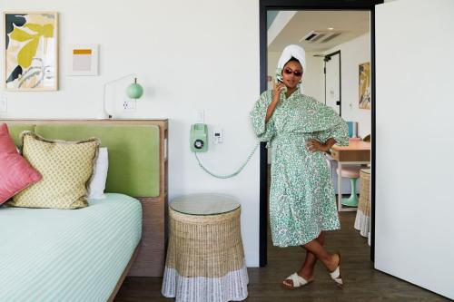 a woman talking on a cell phone in a bedroom at The Goodtime Hotel, Miami Beach a Tribute Portfolio Hotel in Miami Beach