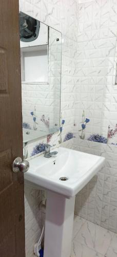 a white bathroom with a sink and a mirror at Heritage Waves in Puri