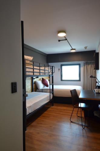 a room with two bunk beds and a desk and a table at ibis budget Sydney East in Sydney