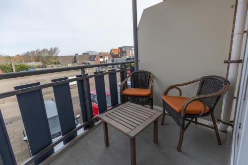 two chairs and a bench sitting on a balcony at Hotel Tesselhof in De Koog