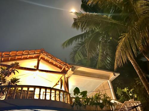 a building with a light on it with palm trees at Janice Villa Arambol in Arambol