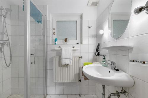 a white bathroom with a sink and a shower at Haus Gartenidylle in Wesselburen