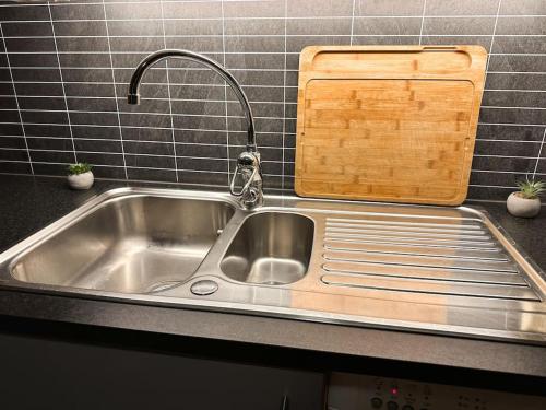 a kitchen sink with a faucet and a cutting board at Hjertet av Stavanger in Stavanger