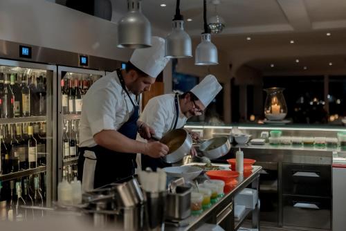 two chefs preparing food in a restaurant kitchen at Hotel Villa Brunella in Capri