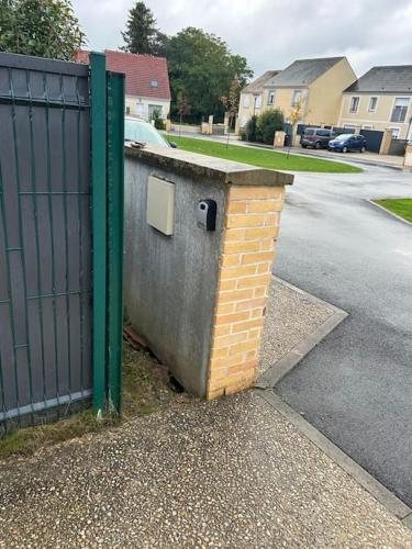 a brick wall next to a gate on a street at Résidence paisible 3 chambres 30 Min Aéroport Roissy CDG in Persan