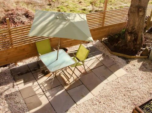 two chairs and an umbrella sitting next to a fence at Pentland Hills Chalet in Edinburgh