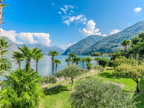a view of a lake with palm trees and mountains at Apartment Sole by Interhome in Claino