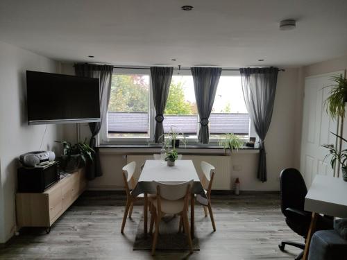 a dining room with a table and chairs and two windows at GeraldineWeg30 -FeWo Geralex in Hessisch Oldendorf