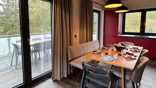 a dining room with a table and a balcony at Hahnenklee Ferienchalets in Hahnenklee-Bockswiese