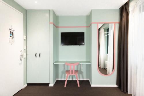 a pink stool in a room with a table and a mirror at Conscious Hotel Vondelpark in Amsterdam