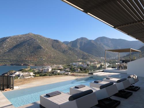 a pool with lounge chairs and a view of the mountains at Cueva Villas, with Pool, SeaViews & close to Sea, By ThinkVilla in Balíon