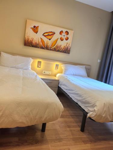 a bedroom with two beds and a painting on the wall at Hostal San Isidro in Autol
