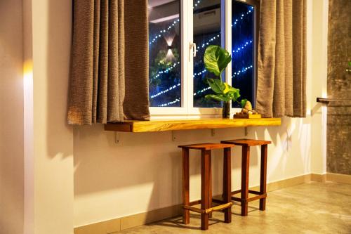 a table with two stools under a window with a plant at Pretty Villa in Gelioya
