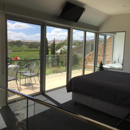 a bedroom with a bed and a balcony with a view at Barossa Shiraz Estate in Lyndoch