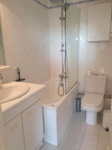 une salle de bain blanche avec toilettes et douche dans l'établissement Duplex au centre de Deauville, à Deauville