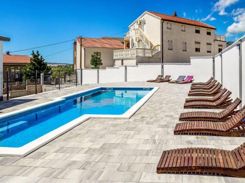a swimming pool with lounge chairs next to a building at Apartment Delfin-9 by Interhome in Cesarica