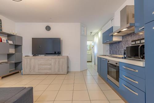 a large kitchen with blue cabinets and a tv at Lugano Station Apartment with FREE PARKING in Lugano
