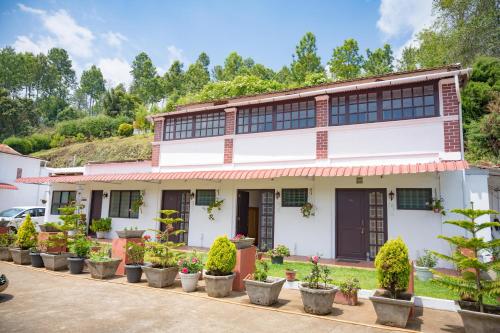 a house with potted plants in front of it at Trilan Cottages - Donnington Road in Kotagiri