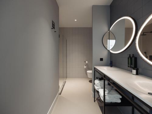 een badkamer met twee wastafels en twee spiegels bij Conscious Hotel Museum Square in Amsterdam
