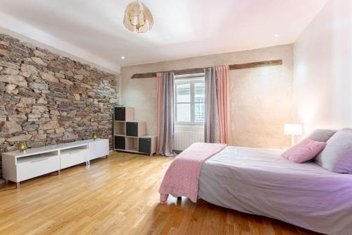 une chambre avec un grand lit et un mur en pierre dans l'établissement Charmant T3 au cœur de Nantes, à Nantes