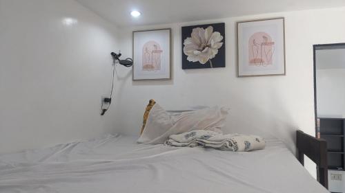 a white bed in a bedroom with pictures on the wall at 102 Casa de Rany in Dumaguete