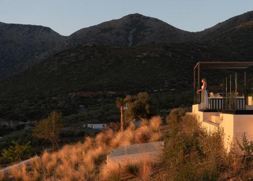 a woman standing on the balcony of a house with mountains at Cueva Villas, with Pool, SeaViews & close to Sea, By ThinkVilla in Balíon