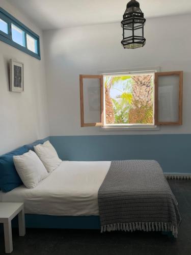 a bed in a room with a window and a couch at Hotel Villa Soleil in Sidi Kaouki