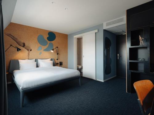 a bedroom with a white bed and a wall with a mural at Conscious Hotel The Tire Station in Amsterdam