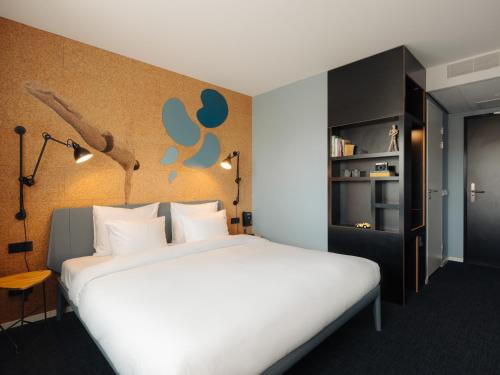 a bedroom with a large white bed and a book shelf at Conscious Hotel The Tire Station in Amsterdam
