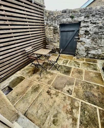 a table and chair on a patio with a door at Queens Cottage in Skipton