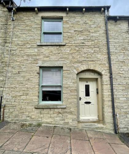 a brick building with a door and a window at Queens Cottage in Skipton