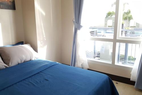 a bedroom with a blue bed and a window at High Ceiling Home by the Pool with Wi-Fi and Netflix in Lapu Lapu City