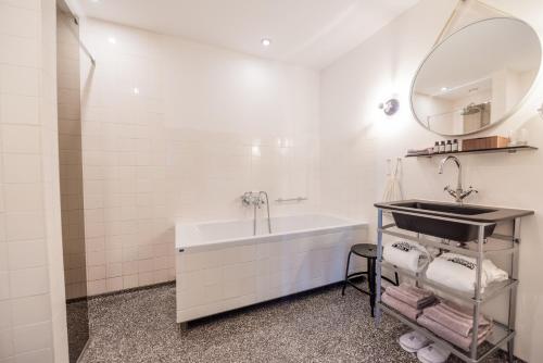 La salle de bains est pourvue d'une baignoire, d'un lavabo et d'un miroir. dans l'établissement Hotel V Nesplein, à Amsterdam
