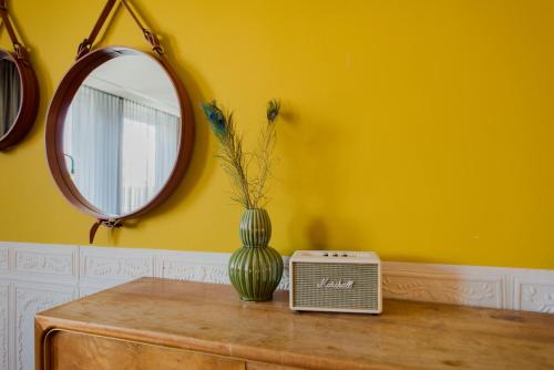 a mirror and a vase on a table with a radio at Hotel V Nesplein in Amsterdam