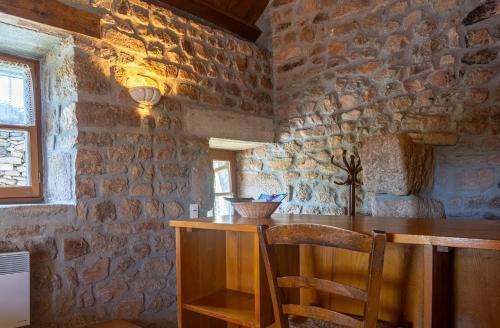 Cette chambre dispose d'une table en bois et d'un mur en pierre. dans l'établissement Le four, ferme de la beyssiere, à Saint-Jean-Chazorne